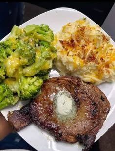 a white plate topped with meat and veggies next to mashed potatoes, broccoli