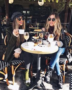 two beautiful women sitting at a table with drinks