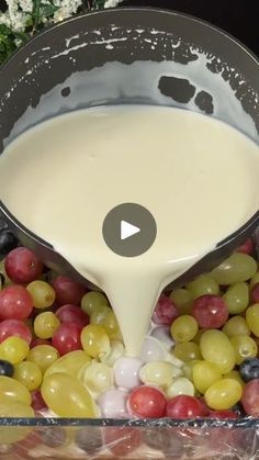 grapes are being poured into a bowl with milk in it and then mixed together to make a fruit salad