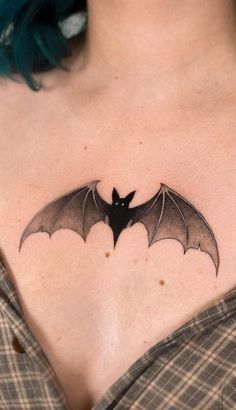 a woman's chest with a black bat tattoo on her left shoulder and right breast