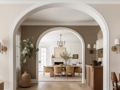 an archway leading to a dining room and living room in a house with beige walls