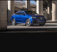 a blue mercedes gle is parked in front of an overpass with concrete pillars