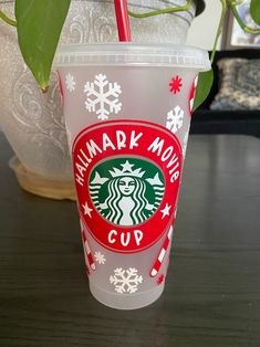 a starbucks cup sitting on top of a wooden table next to a potted plant