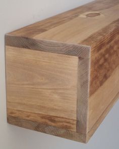 a close up of a wooden shelf on a wall with white walls in the background