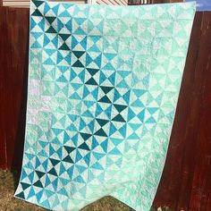 a blue and white quilt hanging on a wooden fence