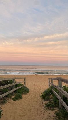 a wooden fence on the beach leading to an ocean