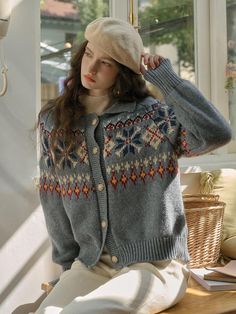 a woman sitting on a window sill wearing a sweater and hat