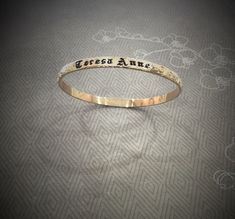 MAKE SURE OF THE SIZE BEFORE ORDERING. 5mm gold filled Hawaiian bangle, 1.70mm thickness. Personalize it with a name or a message engraved and enameled in black. The pattern of plumerias and Victorian scrolls are rolled on a 5mm barrel gold filled wire. All the characters are engraved , not stamped, resulting in straight and aligned name. A black enamel is used to fill in the characters engraved. The maximum number of letters is 15. How Gold filled is made. Gold filled or gold overlay is made by Customizable Gold Bangle For Anniversary, Personalized Gold Stamped Name Bracelet, Personalized Stamped Gold Name Bracelet, Adjustable Gold Bangle With Engraving Option, Gold Bangle With Engraved Text, Engraved Name Bangle Bracelet For Anniversary, Personalized Name Gold Bangle, Engraved Name Bangle For Anniversary, Gold Name Bangle For Anniversary