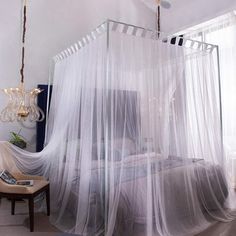 a bedroom with a white canopy bed covered in mosquito netting and a chandelier hanging from the ceiling