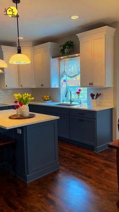 a kitchen with blue cabinets and white counter tops, wooden floors and an island in the middle