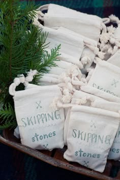 several bags filled with pine needles sitting on top of a wooden tray next to evergreen branches