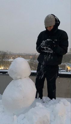 a man standing next to a snowman on top of a roof