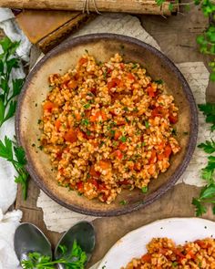 a bowl filled with rice and vegetables on top of a table next to spoons