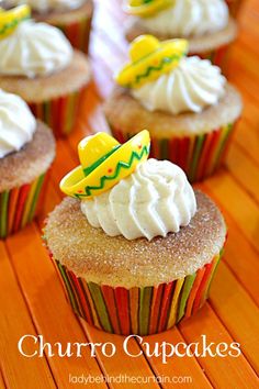 cupcakes with white frosting and decorations on top are sitting on a wooden table