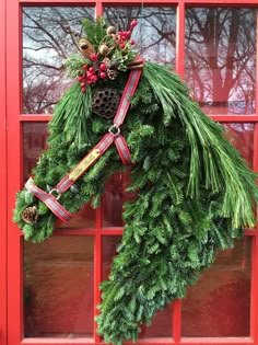 a christmas wreath hanging from the side of a red door