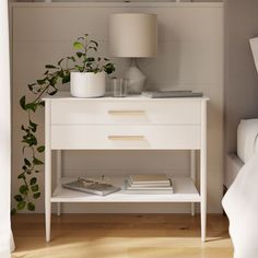 a white nightstand with books and plants on it