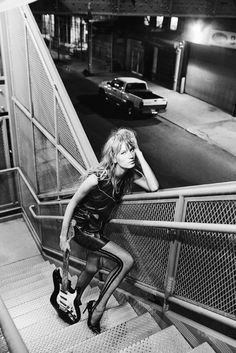 black and white photograph of a woman leaning on the handrail with her legs crossed