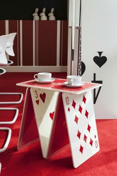 a table with two cups on it in front of a red carpeted floor and wall