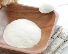 a wooden bowl filled with white powder next to some towels and a flower on a table