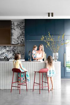 three children are sitting at the counter in this modern kitchen