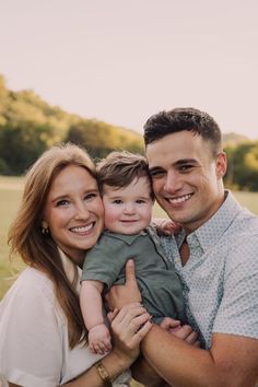 a man and woman holding a small child in their arms while smiling at the camera