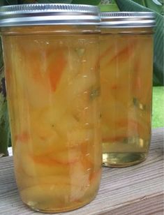 two jars filled with pickles sitting on top of a wooden table