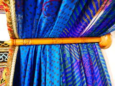 a close up of a bed with blue and purple drapes