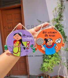 two handmade magnets with cartoon characters on them hanging from strings in front of a house