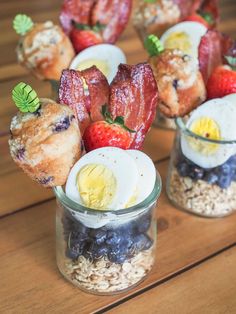 several small cups filled with food on top of a wooden table next to strawberries