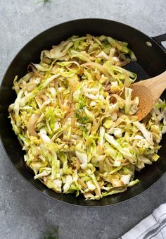 a skillet filled with cooked vegetables and a wooden spoon