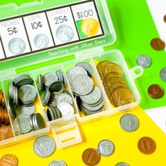 an open plastic box filled with coins on top of a green and white tablecloth