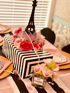 a table topped with plates and flowers next to a black and white striped cake covered in pink roses