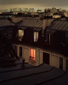 the city skyline is lit up at night with buildings in the foreground and an orange window