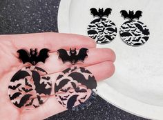 a person holding three bats in front of a white plate with black and white designs on it