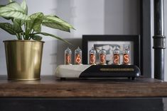 an electronic clock sitting on top of a wooden table next to a potted plant