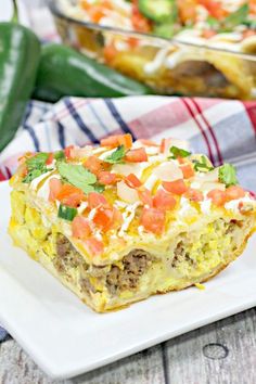 a white plate topped with an enchilada casserole and a dish in the background