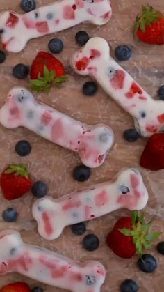 strawberries and blueberries are arranged in the shape of bone shaped dog bones with white icing