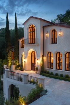 a large white house with lots of windows and lights on the side of it at night