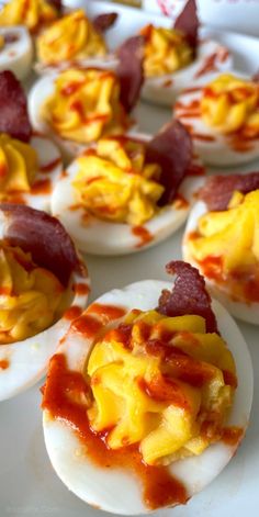 deviled eggs with cheese and ketchup are on a white plate, ready to be eaten