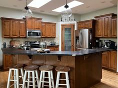 a kitchen with wooden cabinets and stools next to an island in the middle of the room