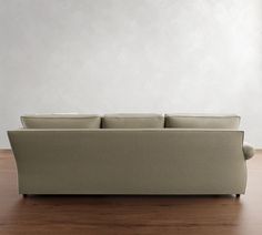 a couch sitting on top of a hard wood floor next to a white wall in an empty room