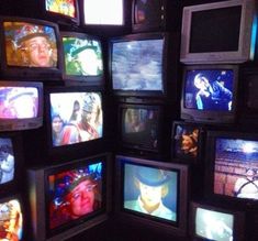 a room filled with lots of different types of tvs on wall next to each other