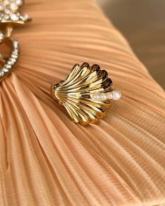 a gold ring sitting on top of a beige cloth with pearls in it's center