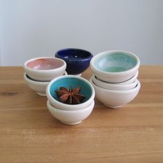 four bowls with star anise in them sitting on a wooden table top next to each other