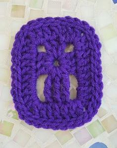 a purple crocheted object sitting on top of a white table next to tiles