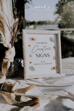 a white frame sitting on top of a table next to a vase filled with flowers