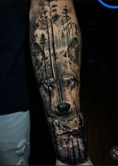 a man's arm with a wolf tattoo on it and trees in the background