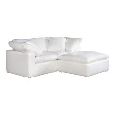 a white sectional sofa with pillows on it's back and side ends, facing the camera