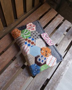 a patchwork wallet sitting on top of a wooden bench