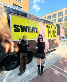 two people standing in front of a truck with the words sweat on it